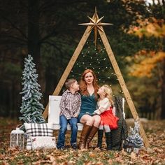 a woman and two children sitting in front of a christmas tree