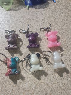 several keychains with different colored teddy bears on them sitting on a counter top