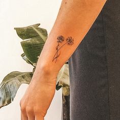 a woman's arm with a flower tattoo on the left side of her wrist