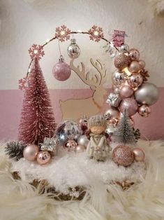 a christmas display with pink and silver ornaments on top of white fur covered flooring