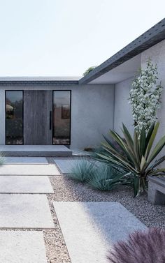 a modern house with stone walkway and plants