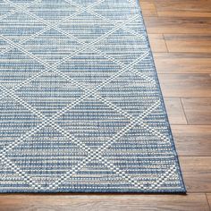 a blue and white area rug on the floor with wood floors in the background,