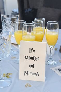 there are many glasses on the table with orange juice in them and a sign that says it's mimosa not minnesota