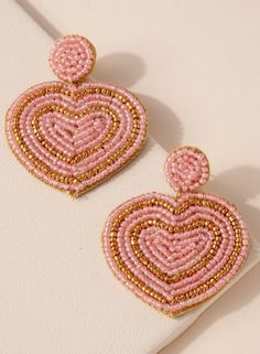 the pink beaded heart earrings are hanging from gold - plated hooks on a white surface