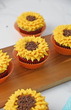 sunflower cupcakes sitting on top of a wooden board