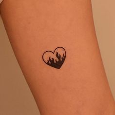 a small tattoo on the leg of a woman's thigh with flames in the shape of a heart