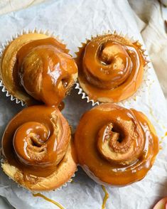 four glazed donuts sitting on top of a piece of paper