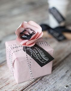 a pink gift box with a flower on it sitting on top of a wooden table