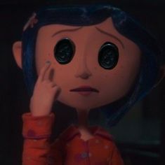 a close up of a doll with big eyes and blue hair, holding her hand to her face