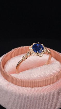 a ring with a blue stone in it on top of a pink velvet band,