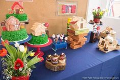 a table topped with cakes and cupcakes on top of blue cloth covered tables