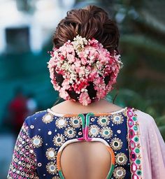 the back of a woman's head with flowers in her hair and dress on