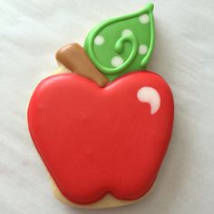 a cookie shaped like an apple with a green leaf and letter g on it's side