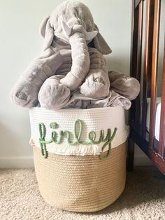 an elephant stuffed animal sitting on top of a basket with the word perley spelled in green