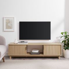 a flat screen tv sitting on top of a wooden entertainment center in a living room