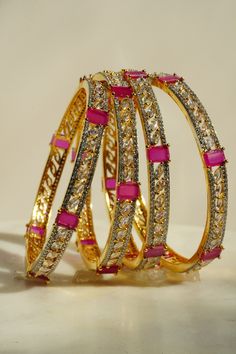 Elevate your style with the Sanya AD Bangle Set, which offers three enchanting options to match your mood and attire. Choose from dazzling gold plated with ruby-colored AD stones, sleek rhodium plated with sapphire blue AD stones, or chic rhodium plated with purple AD stones and white AD stones. Crafted with high-quality square and petal-cut stones, these bangles radiate elegance, sophistication, and unique glamour. Each set includes four bangles, ensuring you shine with high-quality, durable, a Gold Ruby Bangle, Hand-set Ruby Bracelets In Gold, Hand-set Ruby Gold Bracelets, Hand Set Ruby Bracelets In Gold, Gold Ruby Bracelets With Hand Set Stones, Elegant Gold Bangle With Ruby, Gold Bracelets With Stone Setting For Party, Gold Ruby Bracelets For Party, Gold Ruby Bracelet For Party