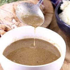 a spoon is pouring gravy into a bowl