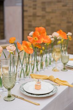 the table is set with plates and glasses, flowers in vases, and napkins