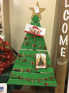 a christmas tree made out of popsicle sticks with pictures pinned to the top and attached to clothes pins