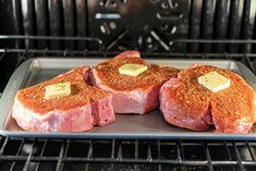 three pieces of meat sitting on top of a pan in an oven, with butter and seasoning