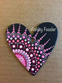 a black heart with pink and white designs on it that says ashley feederer