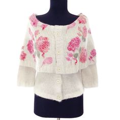 a white sweater with pink flowers on it and a black mannequin headdress