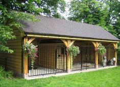 a dog house with two dogs in it and some flowers on the fence around it