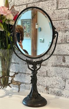 a mirror sitting on top of a table next to a vase filled with flowers