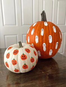 two pumpkins with ghost faces on them are sitting on a table next to each other