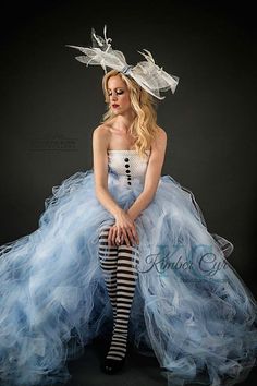 a woman in a blue and white dress sitting on top of a black floor with her legs crossed