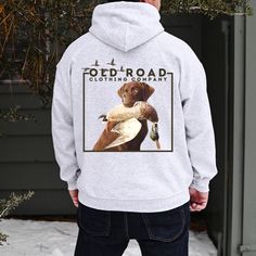 a man standing in front of a house wearing a sweatshirt with a duck on it