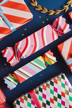 many different colored wrapping paper on a blue surface with gold and red decorations around it