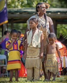 an image of native people standing in the grass with other people behind them looking at something