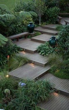 an outdoor garden with wooden steps and plants on each side, surrounded by greenery