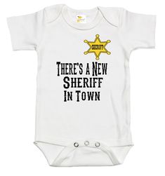 Rapunzie's lovely and endearing baby onesie, which was created specifically for the young ones who are capable of taking charge. This short-sleeved onesie is produced with the highest care and is composed of 100% cotton to keep your baby comfortable all day. Your child is guaranteed to steal hearts and rule the nursery thanks to its charming image of a sheriff's badge and the humorous tagline "There's a New Sheriff in Town."With sizes ranging from 0 to 3 months, 3-6 months, 6 to 12 months, and 1 Funny Short Sleeve White Onesie, Funny White Short Sleeve Onesie, White Unisex Short Sleeve Onesie, Cotton Onesie With Funny Text And Short Sleeves, Cotton Short Sleeve Onesie With Funny Text, Funny Short Sleeve Onesie, The Young Ones, Sheriff Badge, Boy Baby