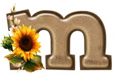 the letter m is made up of sand and has a sunflower in it's center