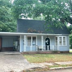 a small blue house sitting in the middle of a yard next to a tree and grass area