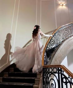 a woman in a white dress is walking down the stairs