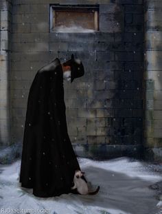 a cat sitting next to a man in a black cape and cloak on a snowy day