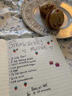 a recipe book with strawberries and muffins on it next to an open notebook