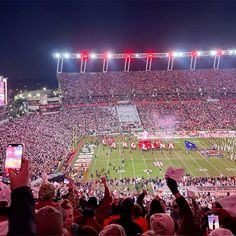 a football stadium filled with lots of people and fans holding up their cell phones to take pictures