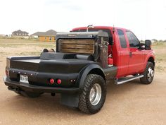 a red pick up truck parked on top of a dirt field