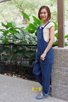 a woman standing in front of a building with her hand on her hip and smiling at the camera