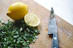 a cutting board with lemons, parsley and a knife