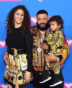 a man and woman standing next to a child on a red carpet at an awards event