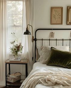 a bed with white sheets and pillows in a bedroom next to two framed pictures on the wall