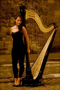 a woman standing next to a large harp