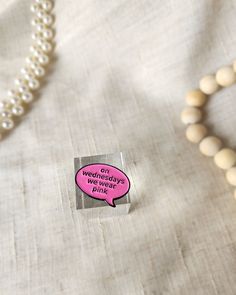 a white bead necklace with a pink speech bubble on it next to a pearl necklace