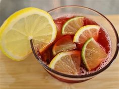 a pitcher filled with liquid and sliced lemons on top of a wooden cutting board