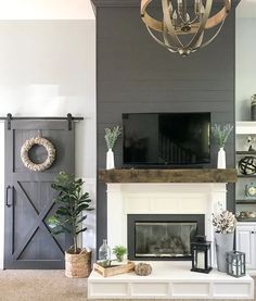 a living room with a fireplace, tv and other decorations on the mantle in front of it